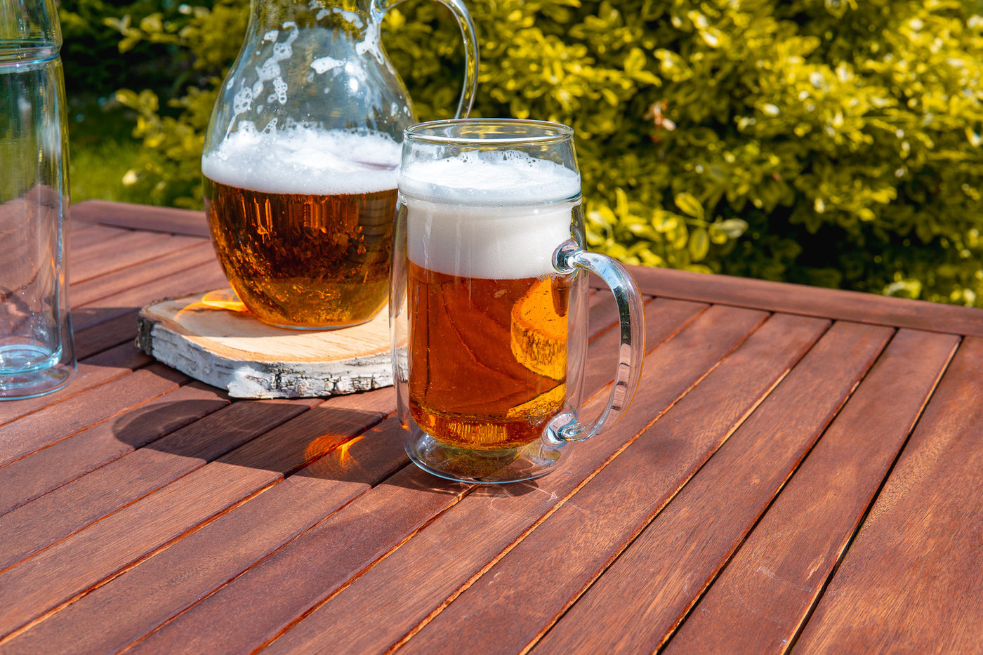 Dvoustěnný skleněný půllitr na pivo s uchem Simax na zahradním dřevěném stole