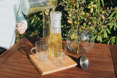 Otevřená skleněná karafa na čaj Simax Indis při nalévání čaje na zahradním stole