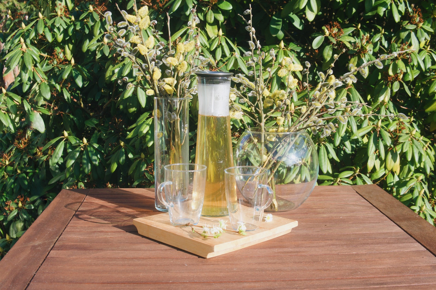 Kulatá skleněná váza Simax Globe a skleněná karafa Simax Indis na zahradním dřevěném stole