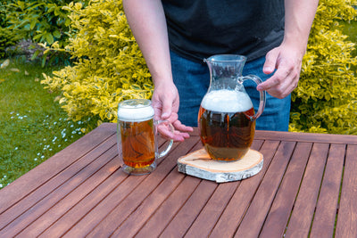 Skleněný pivní džbán a skleněný půllitr na pivo s uchem na venkovním stole