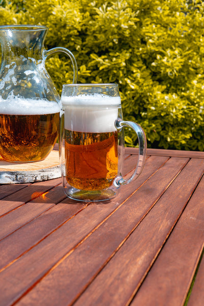 Skleněný půllitr na pivo s uchem Simax na zahradním dřevěném stole na jaře