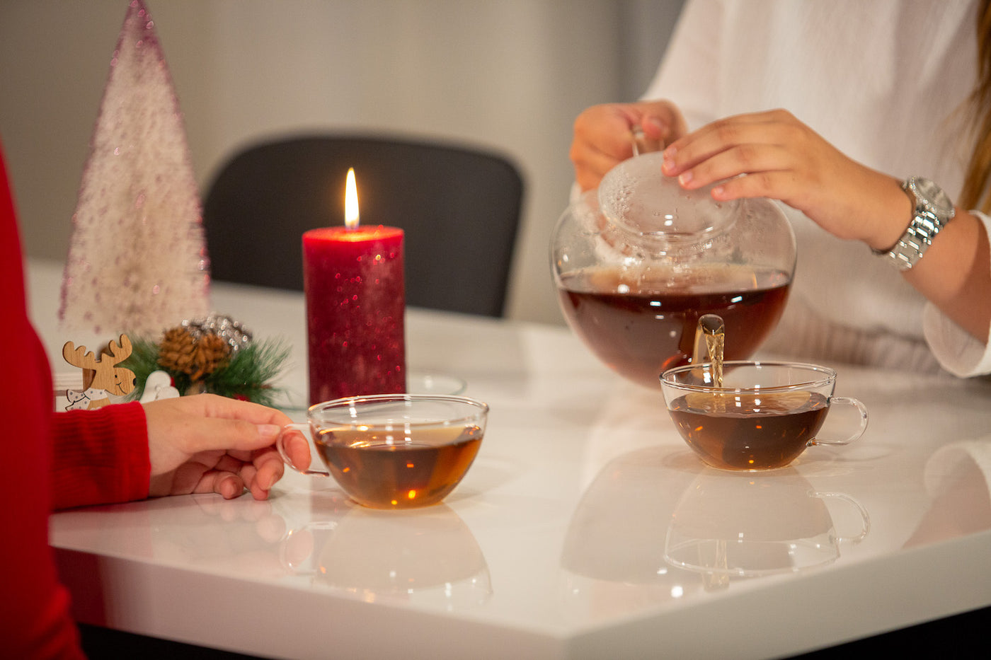 Čajová skleněná konvice Simax Saturn na stole s vánoční svíčkou