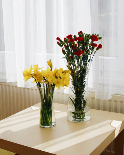 Skleněné vázy Simax Rose se žlutými a červenými květinami na stole