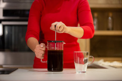 Skleněný french press s kávou a sklenice Simax Lyra na kuchyňské lince
